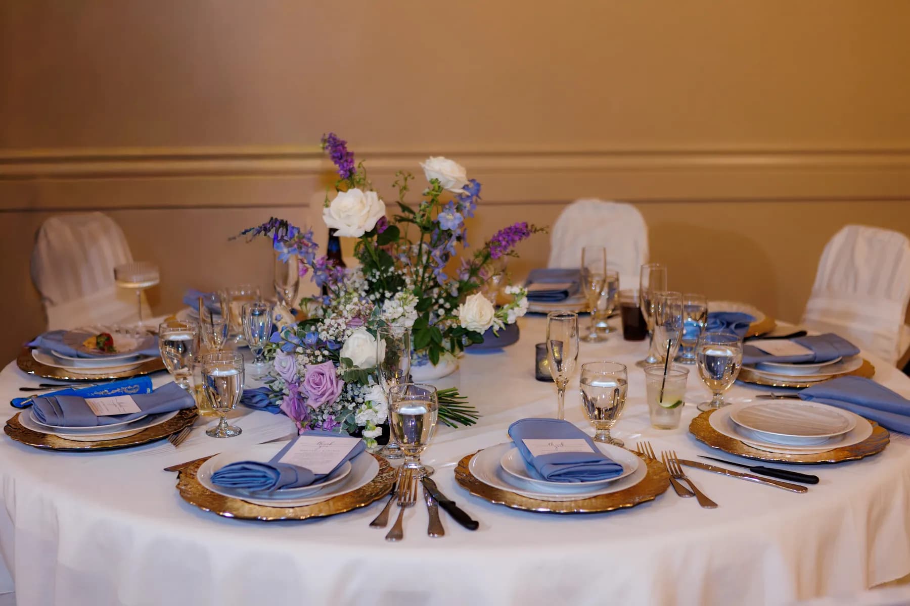 Round reception table with lavender and blue flowers and blue napkins