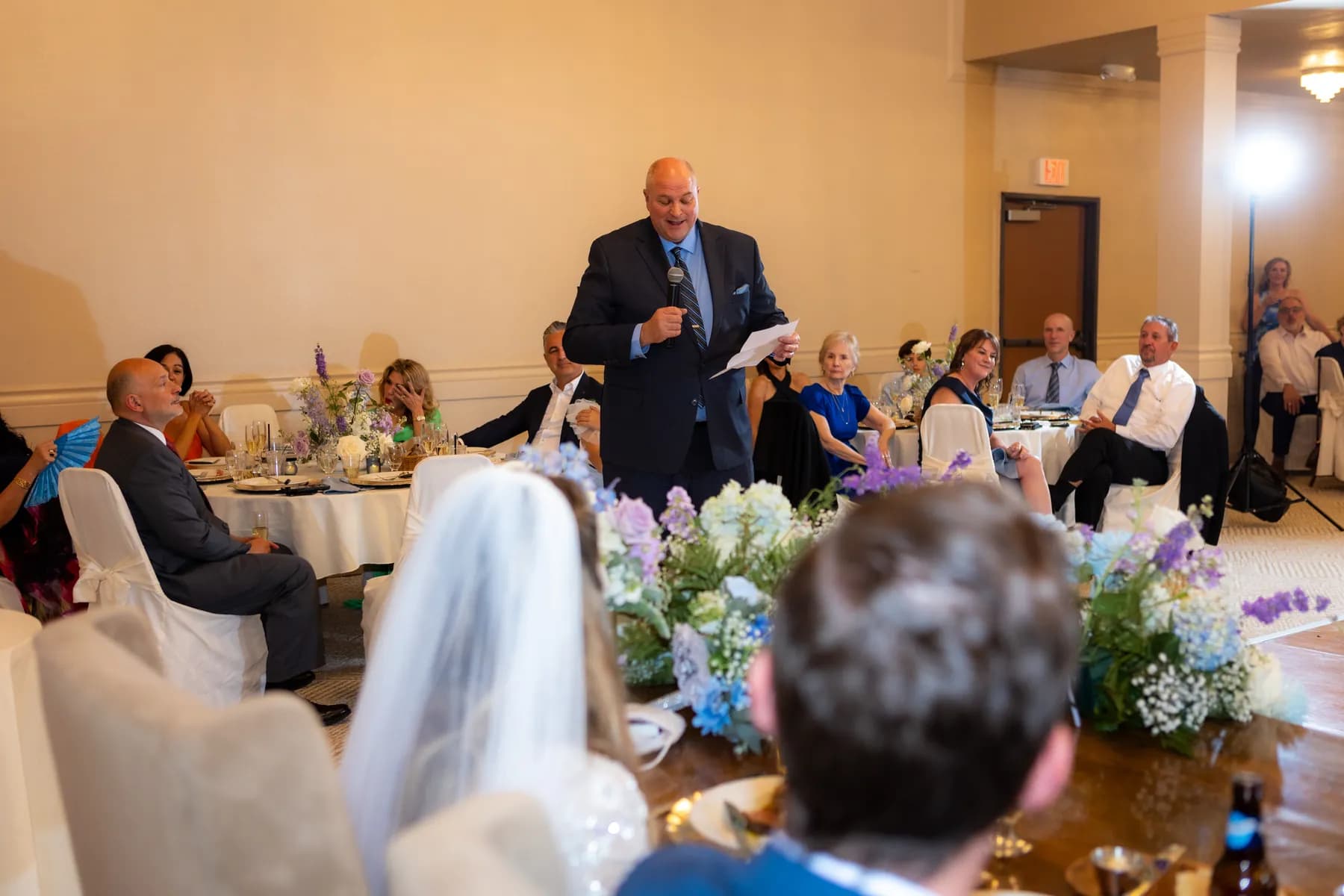 A man speaking while guests watch at the reception