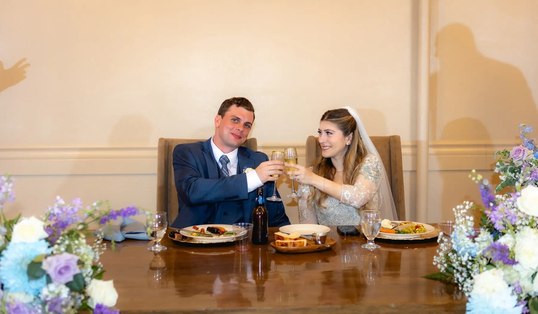 Gloria and Ryan raising glasses together at the reception table