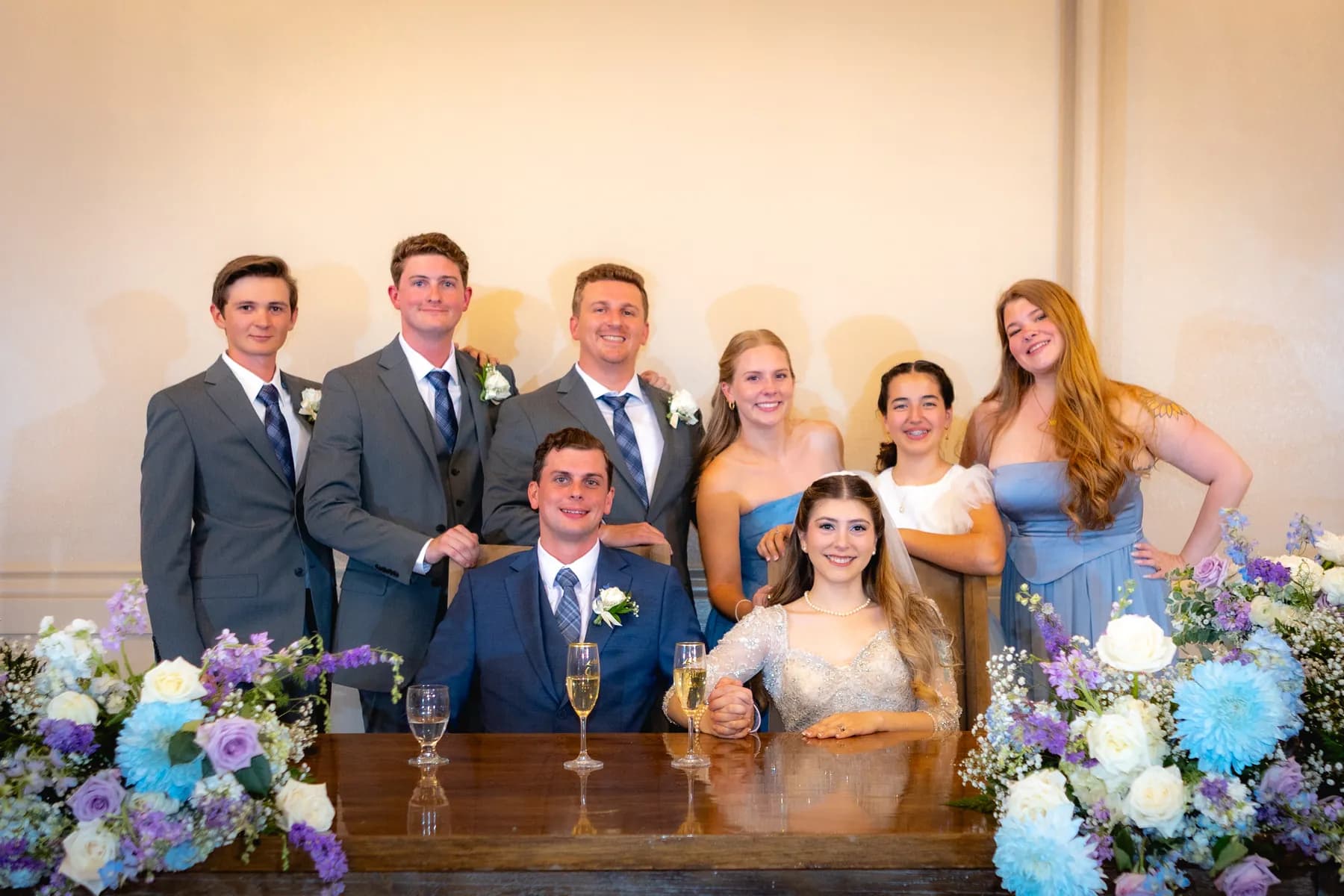 Gloria and Ryan seated with companions behind floral table arrangements