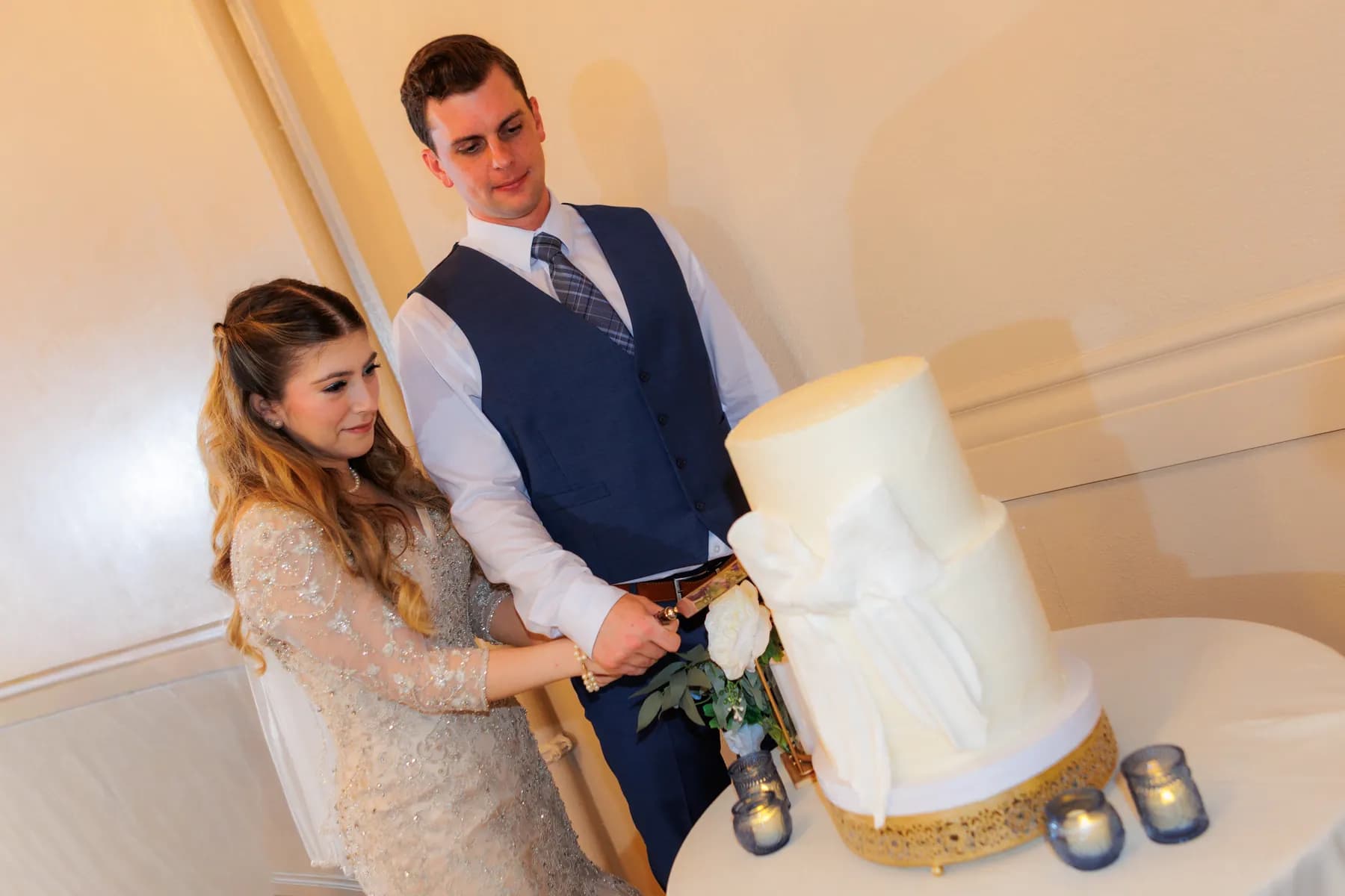 Gloria and Ryan cutting their white tiered wedding cake