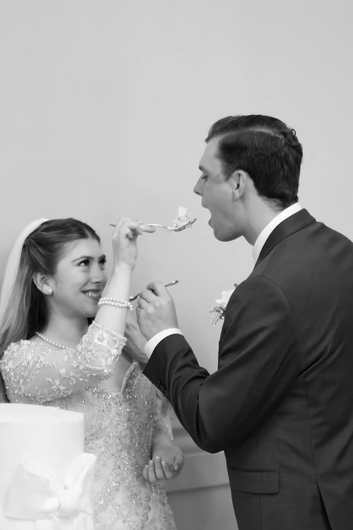 Black-and-white portrait of Gloria and Ryan sharing wedding cake