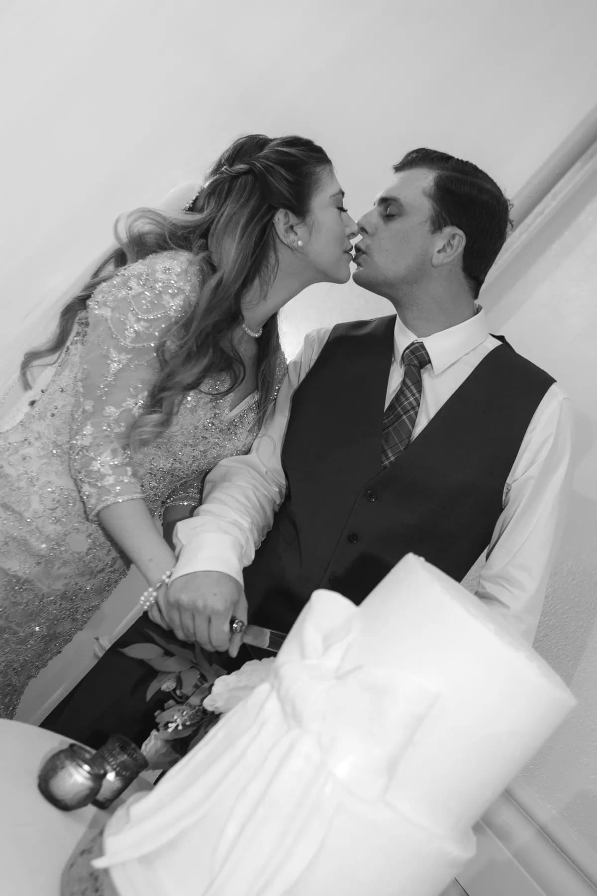 Gloria and Ryan close together beside the wedding cake in black and white