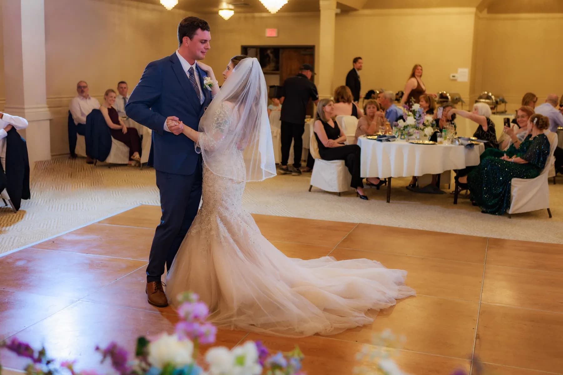 Gloria and Ryan dancing with reception tables behind them