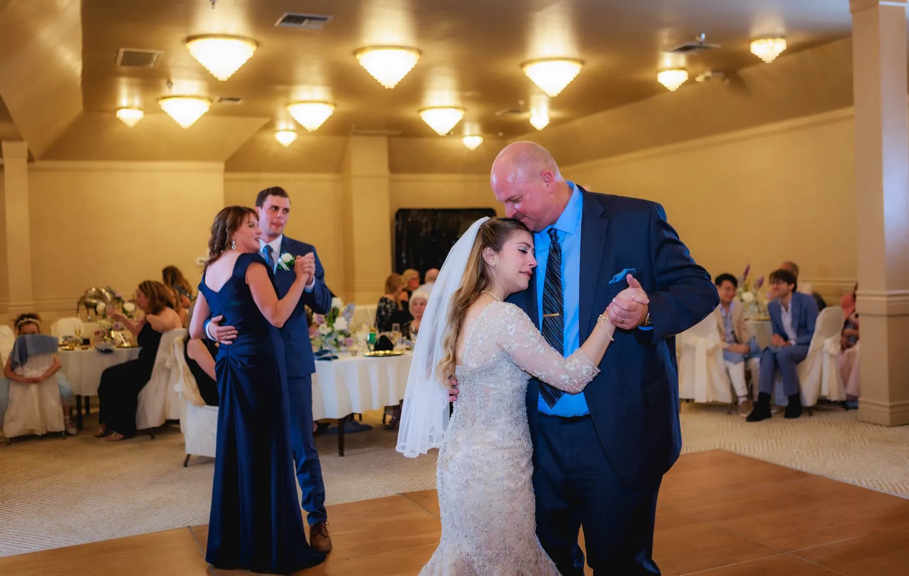 Gloria dancing with a man in a blue suit at the reception