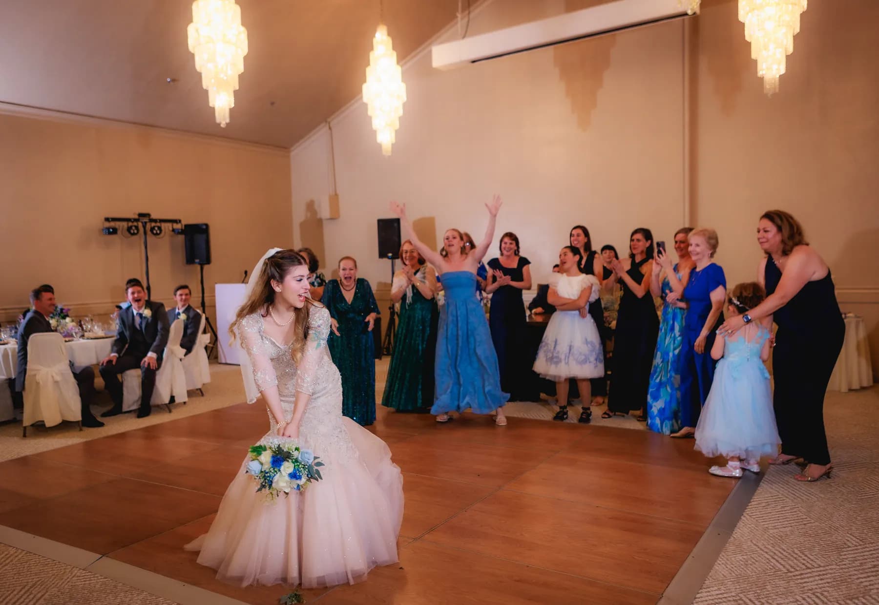 Gloria standing with her bouquet as guests dance behind her