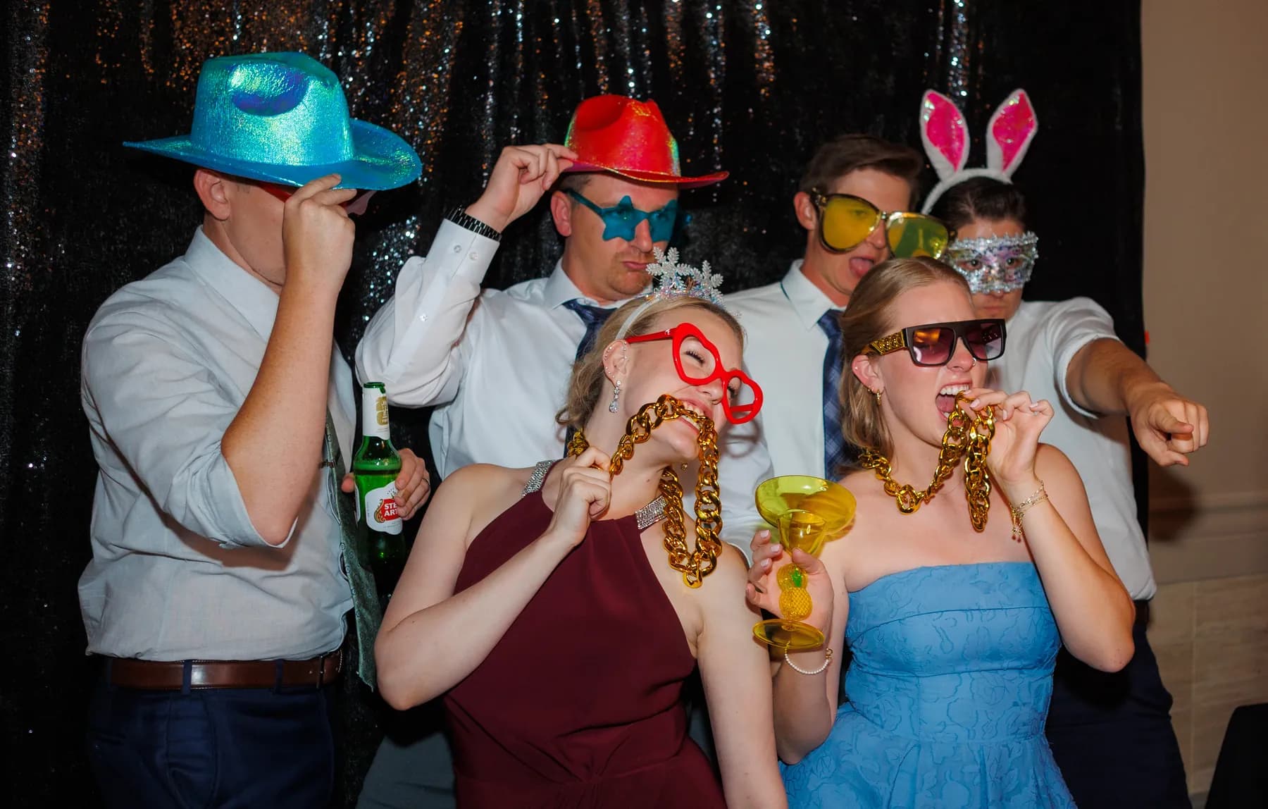 Guests wearing colorful party hats and glasses at the reception