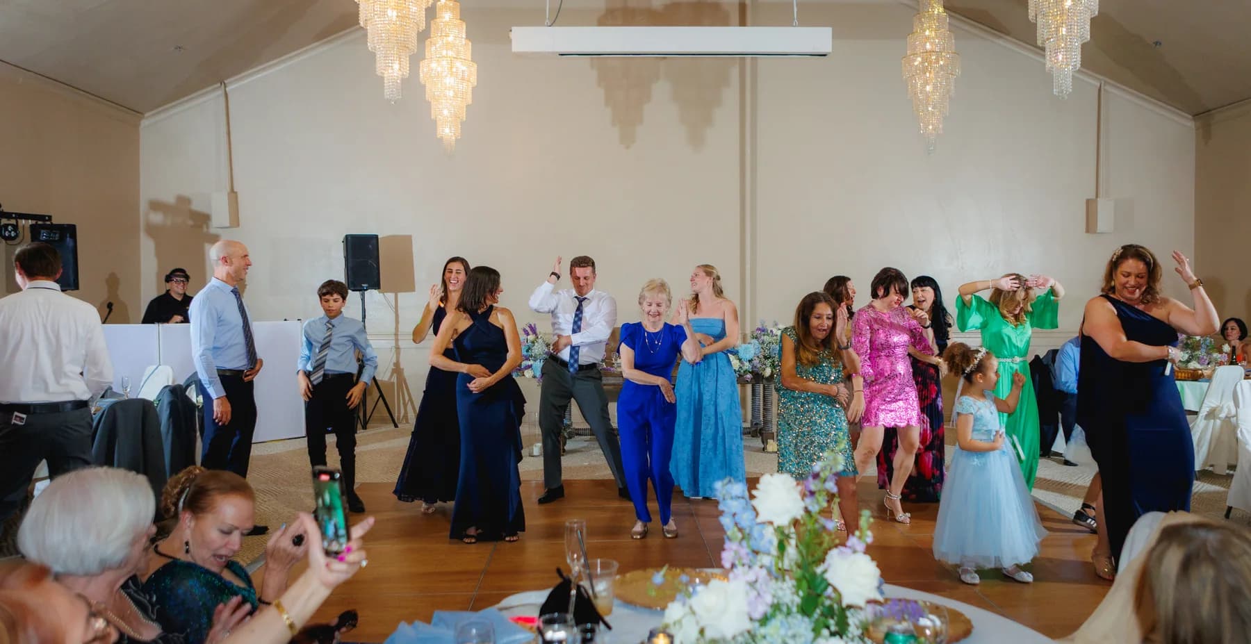 Guests dancing beneath chandeliers at Gloria and Ryan's reception