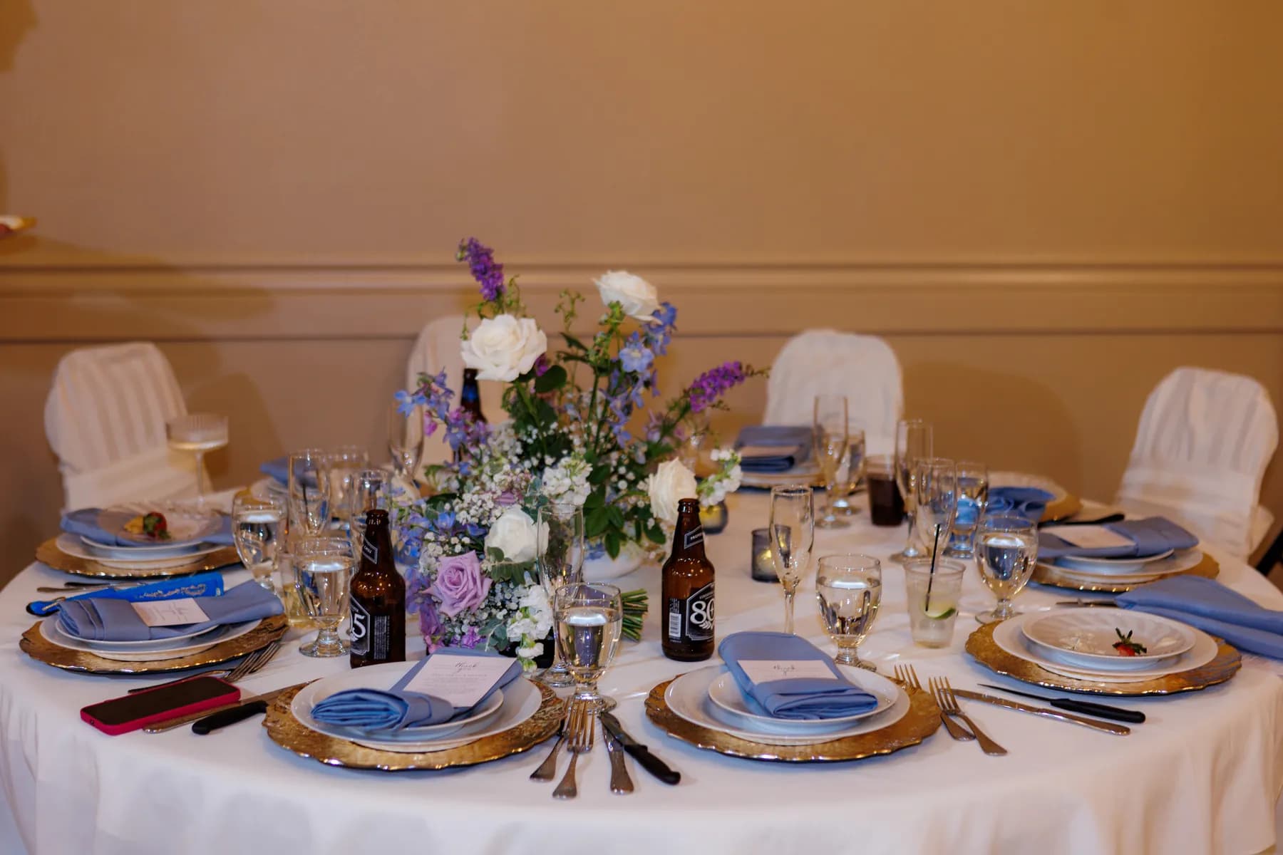 Reception table set with flowers, blue napkins, and glassware