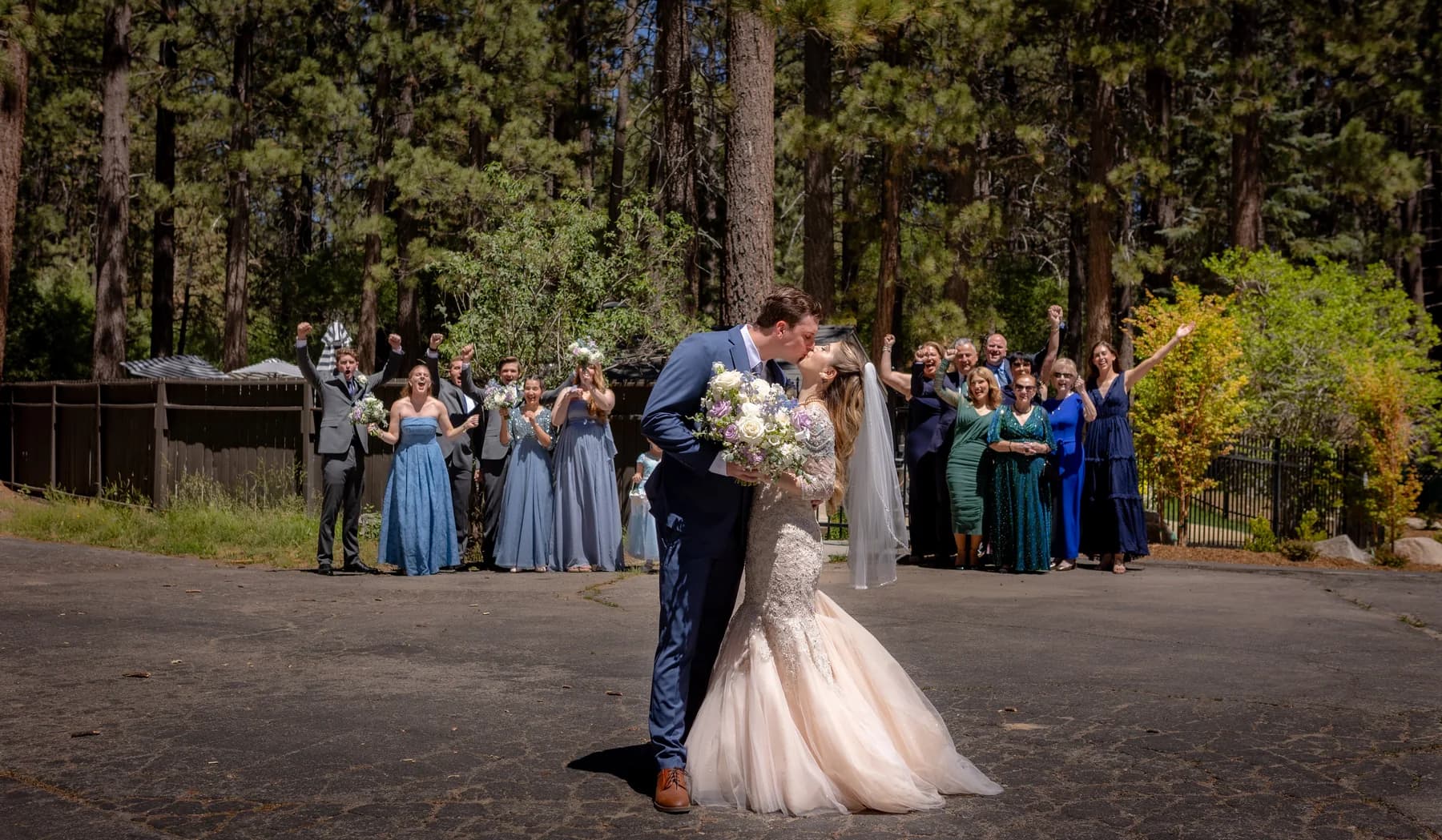 Gloria and Ryan kissing with their wedding group cheering behind them