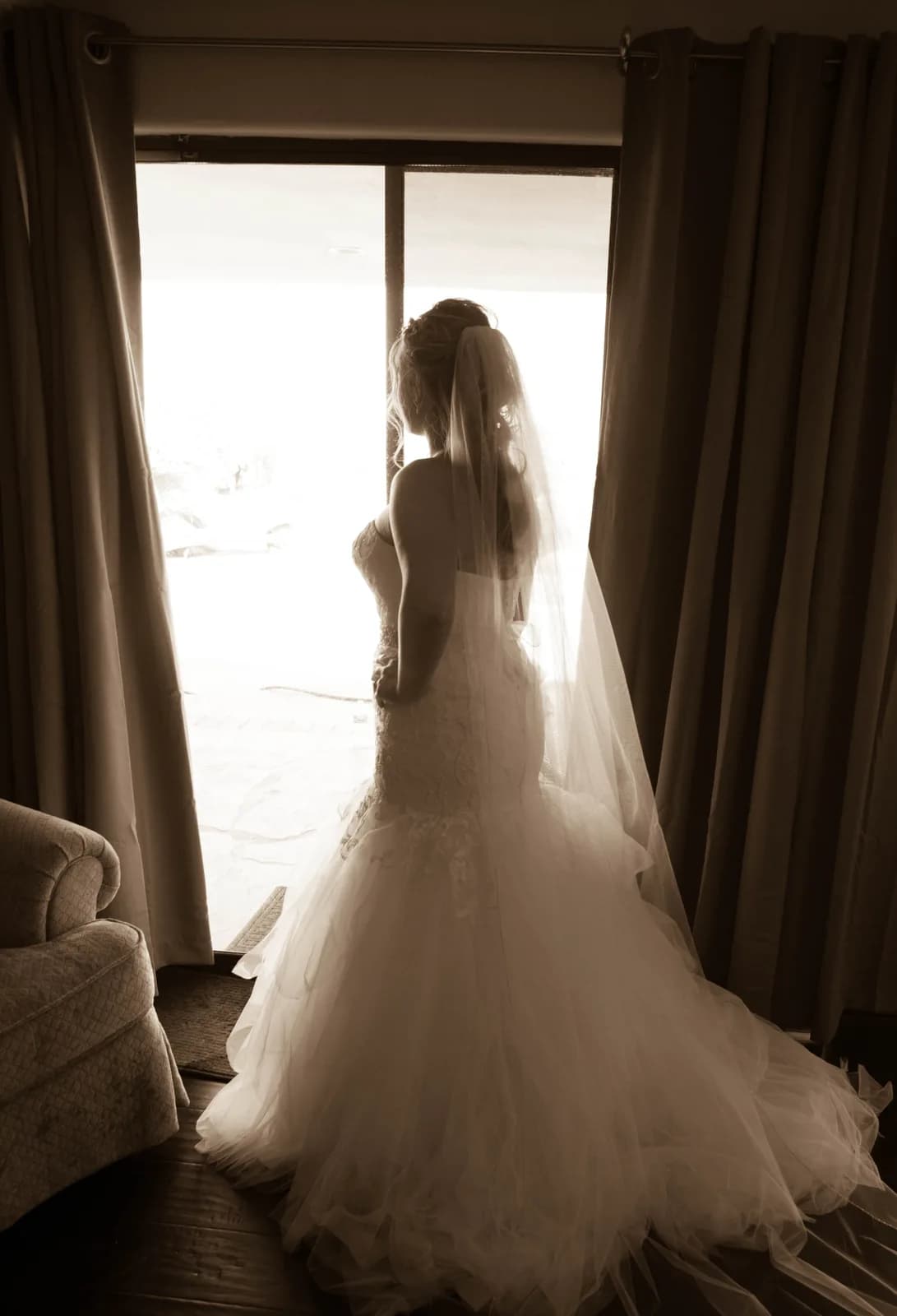 Heather standing beside her wedding dress in soft window light