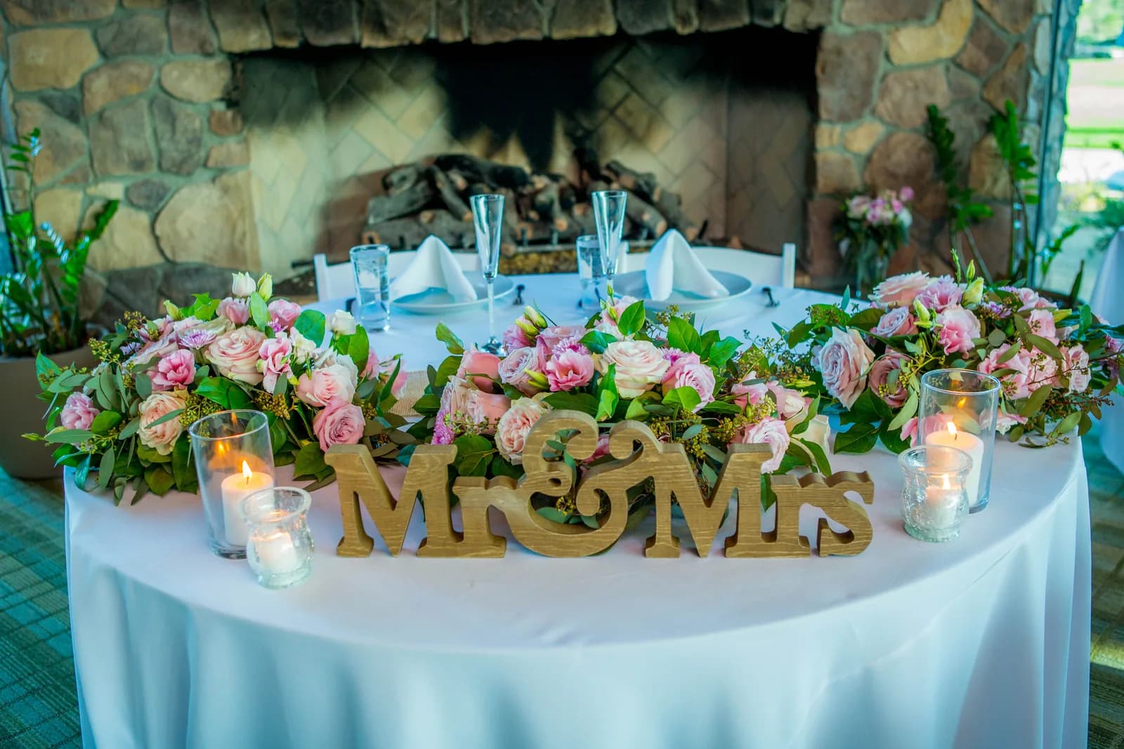 Wedding reception table decorated with pink flowers and candles