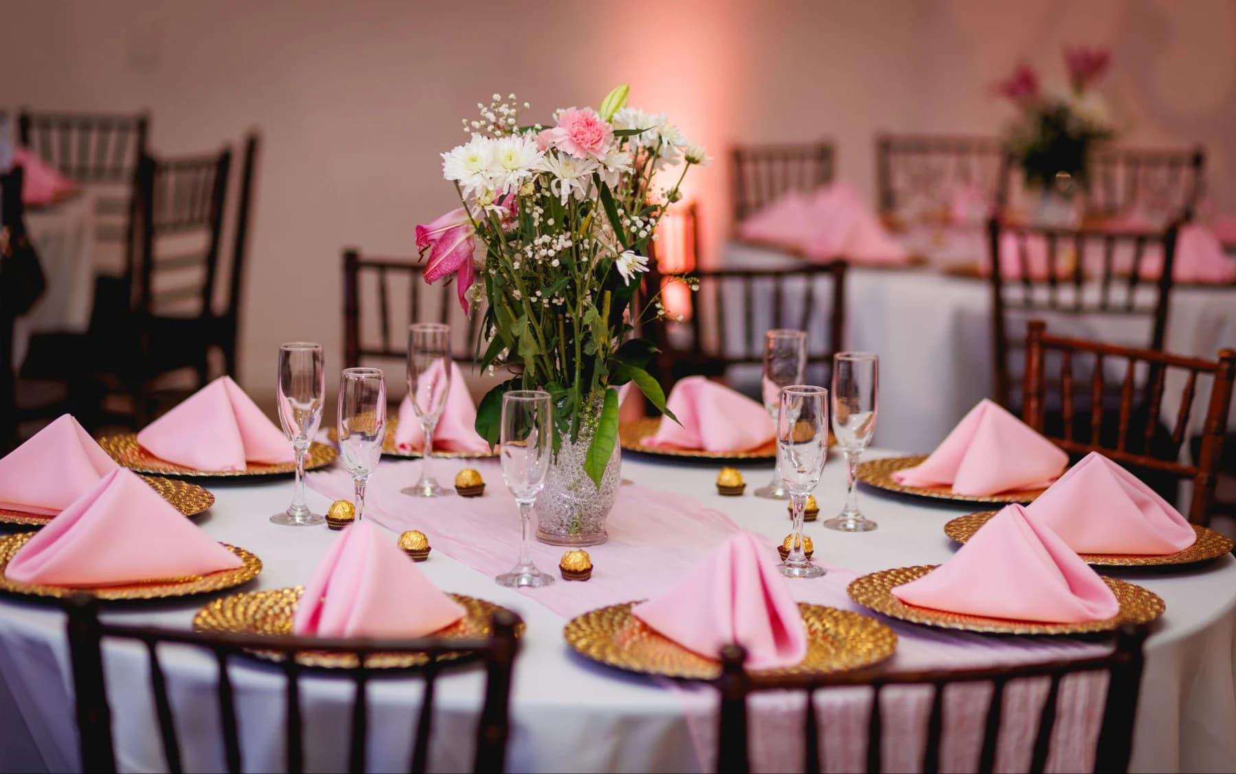 Reception table with pink napkins and a tall floral centerpiece