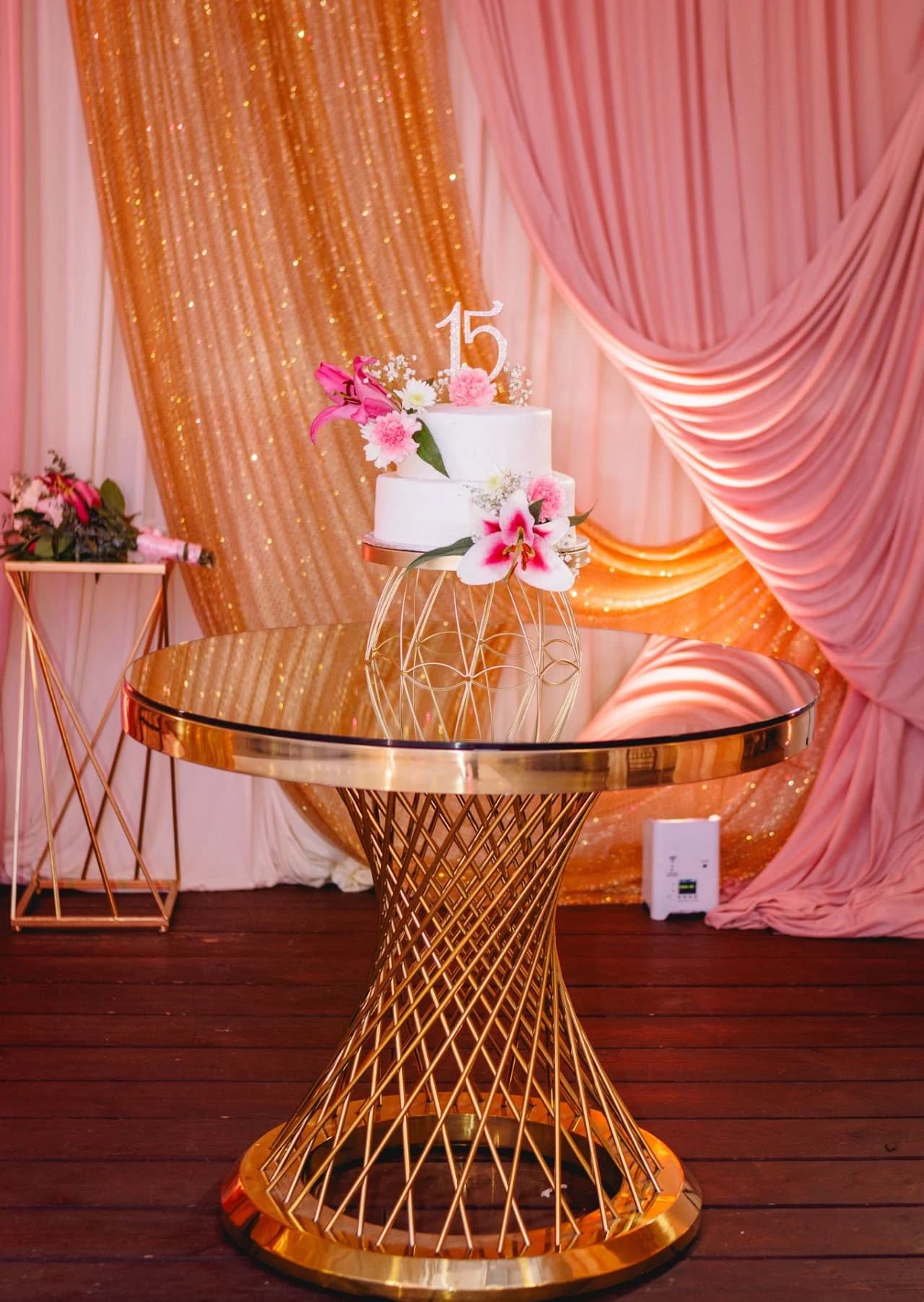 Pink cake on a gold table against drapery