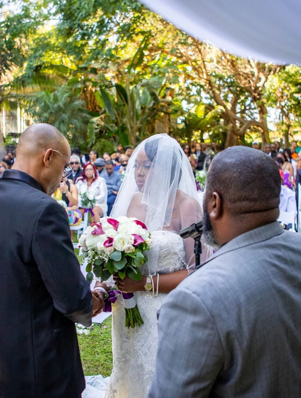 View through seated guests toward the couple at the arbor