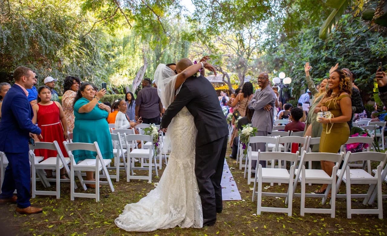 Couple kissing in the aisle as guests stand around them