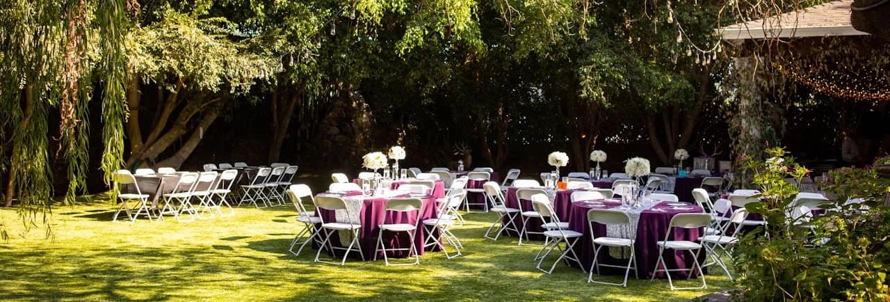 Reception tables arranged beneath leafy trees