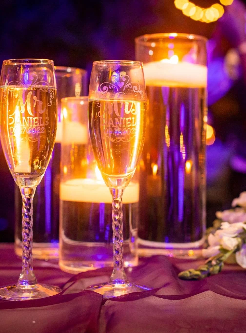 Warm candlelight reflected in reception glassware