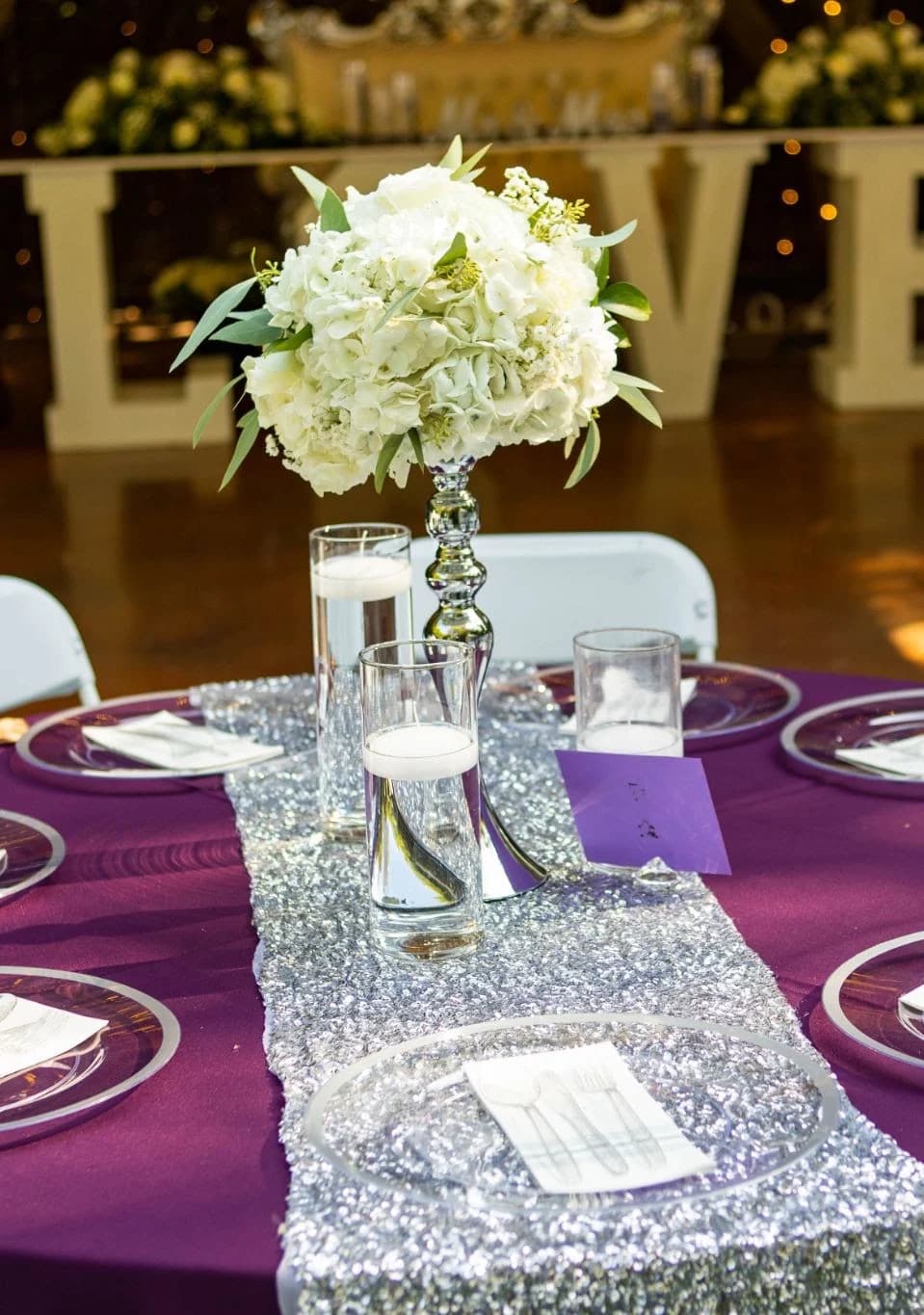 White flowers and a purple runner on a reception table