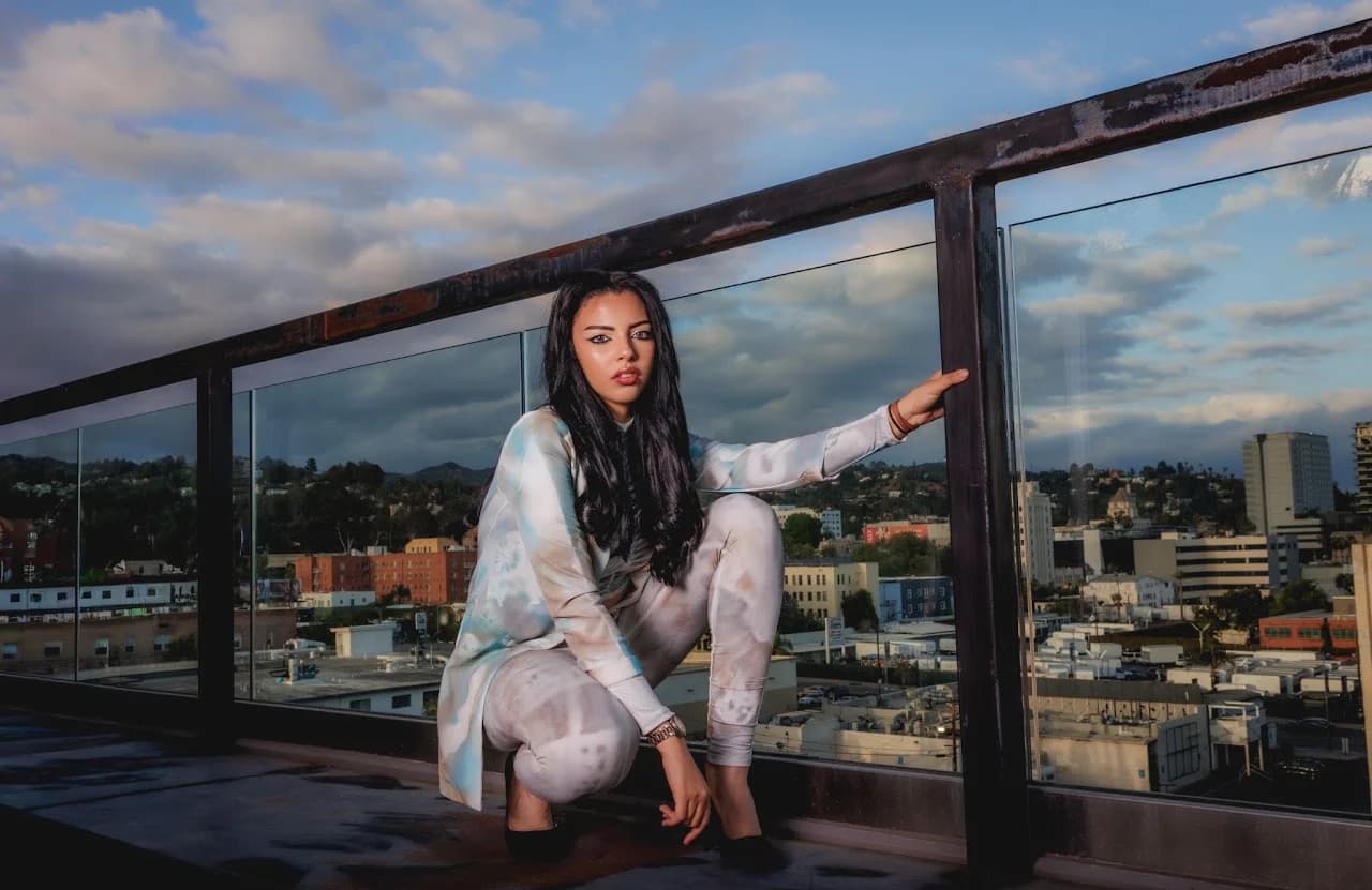Crouching fashion pose beside a glass railing