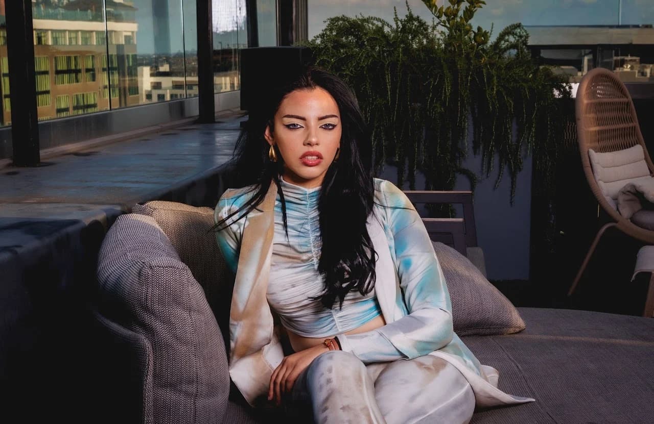 Seated model with an arm resting on a sofa