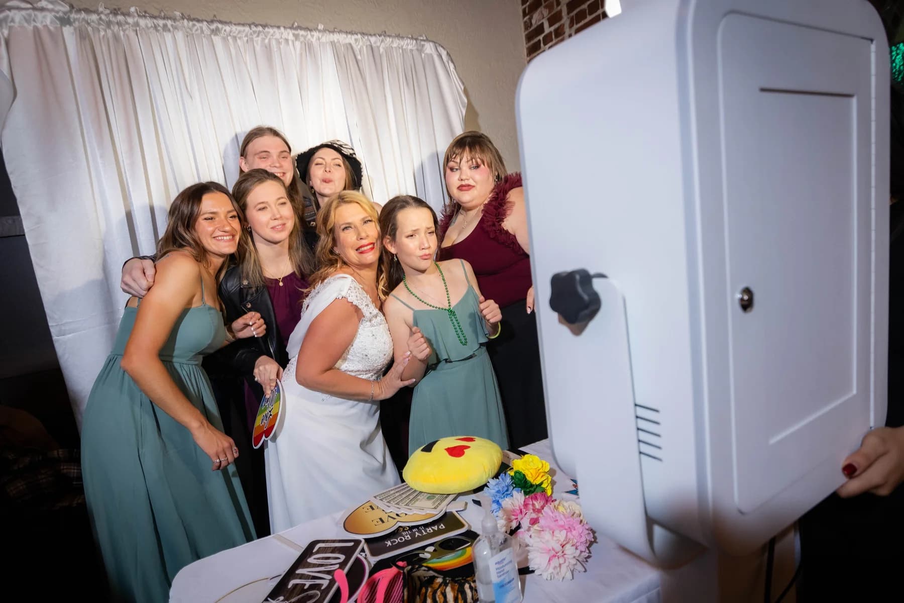 Wedding party gathering around a photobooth for a playful group portrait