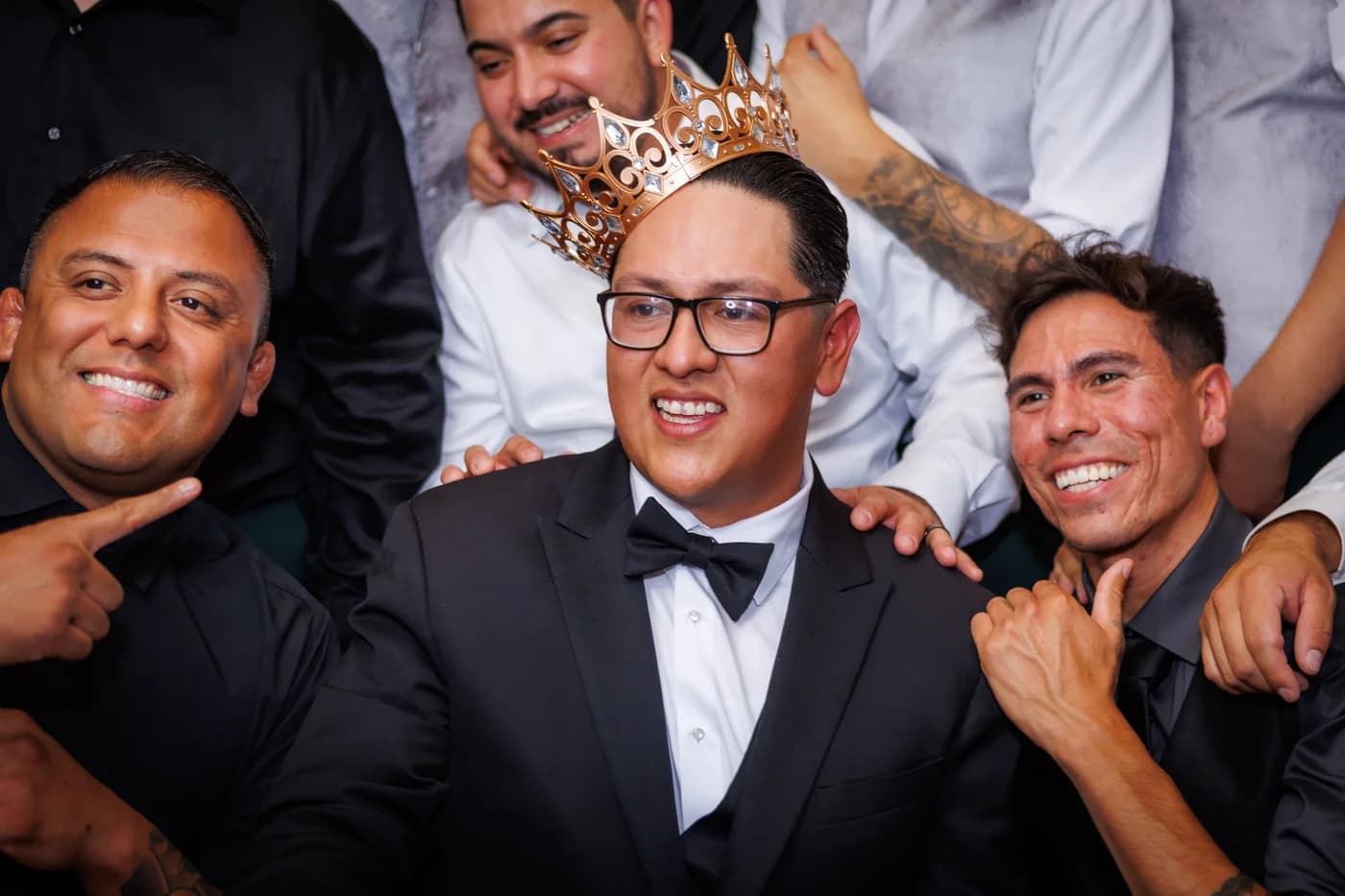 Wedding guests smiling around the groom during a photobooth portrait