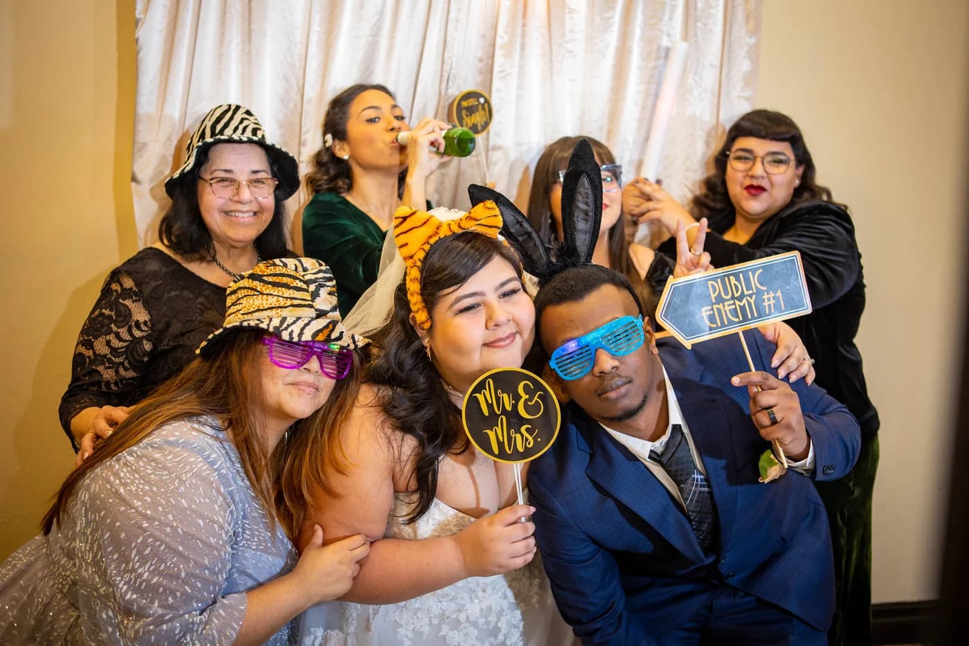 Newlyweds and wedding guests posing together with colorful photobooth props